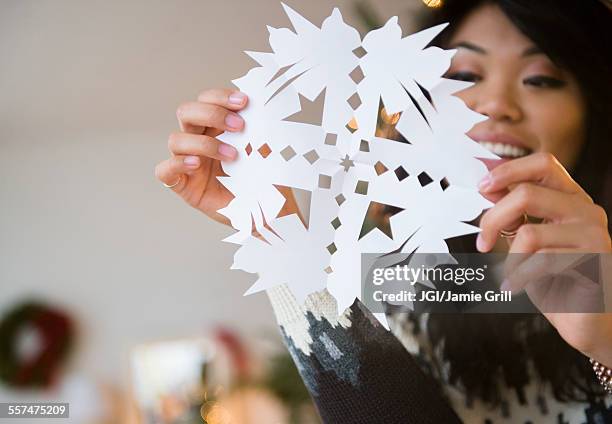 pacific islander woman holding paper snowflake - paper snowflakes stock-fotos und bilder