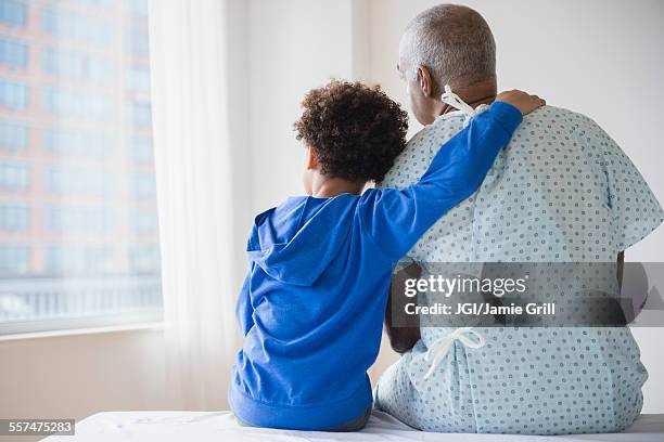 mixed race grandfather sitting with grandson in hospital - mixed race family stock-fotos und bilder