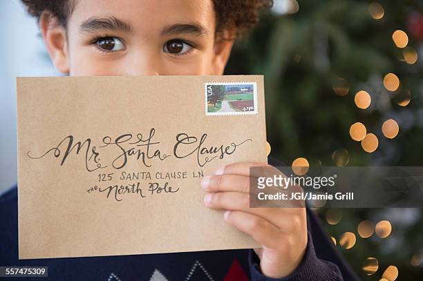 mixed race boy holding letter to santa for christmas - greeting card and envelope stock pictures, royalty-free photos & images