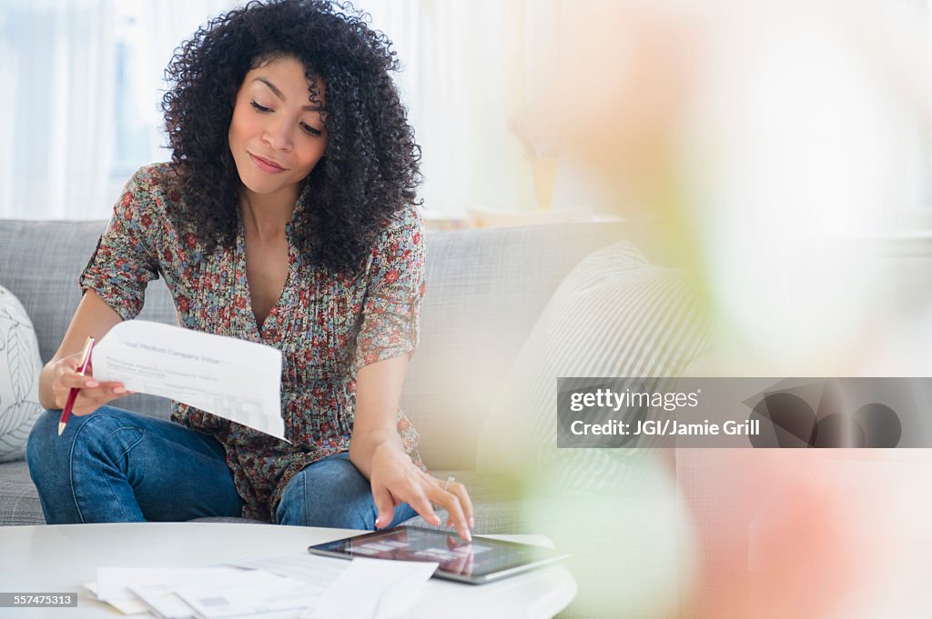 Mixed race woman paying bills on digital tablet