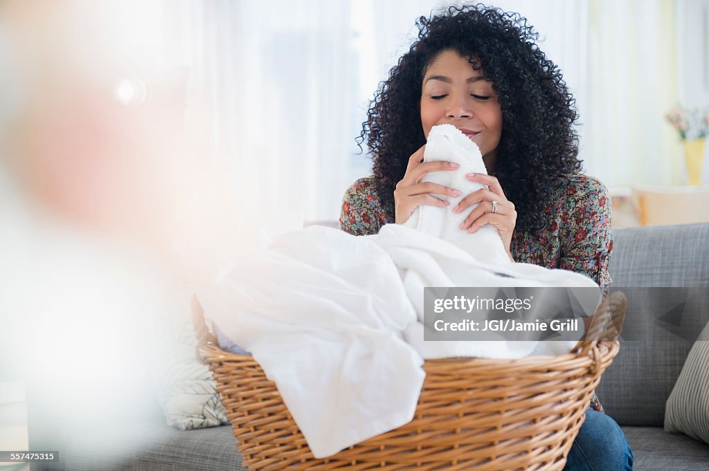 Mixed race woman smelling clean towels in laundry