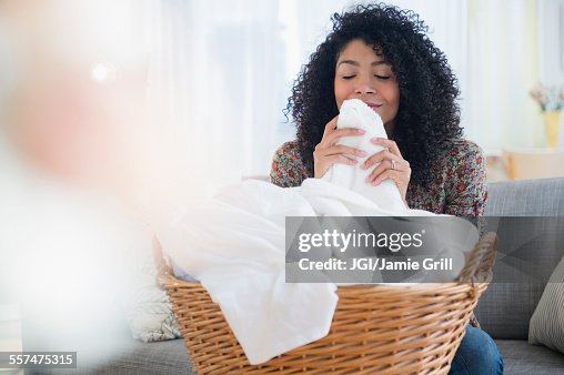 Mixed race woman smelling clean towels in laundry Mixed race woman smelling clean towels in laundry