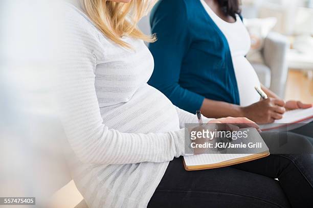 pregnant women taking notes in class - prenatal class stock-fotos und bilder