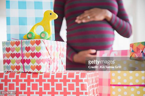 black pregnant woman admiring gifts at baby shower - babyshower stockfoto's en -beelden