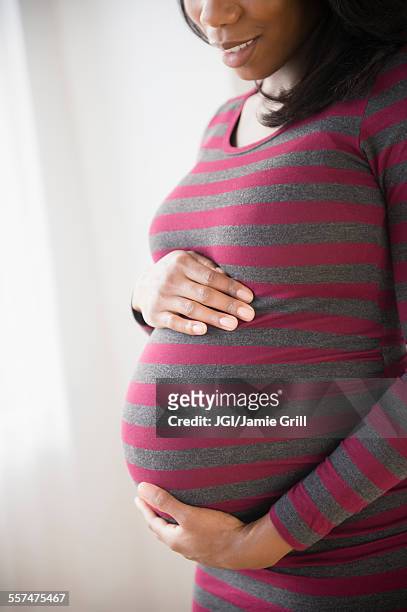 black pregnant woman admiring her stomach - striped dress stock pictures, royalty-free photos & images