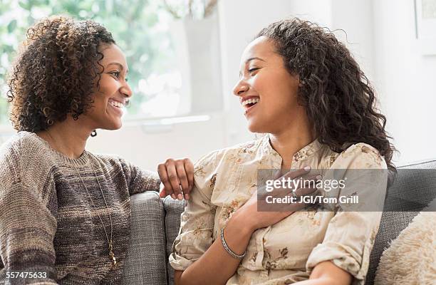 laughing women talking on sofa - sister photos et images de collection