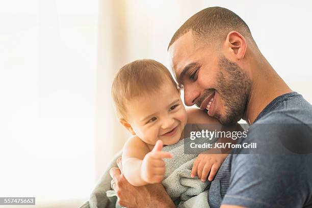 father drying baby son with towel after bath - baby father hug side stock-fotos und bilder