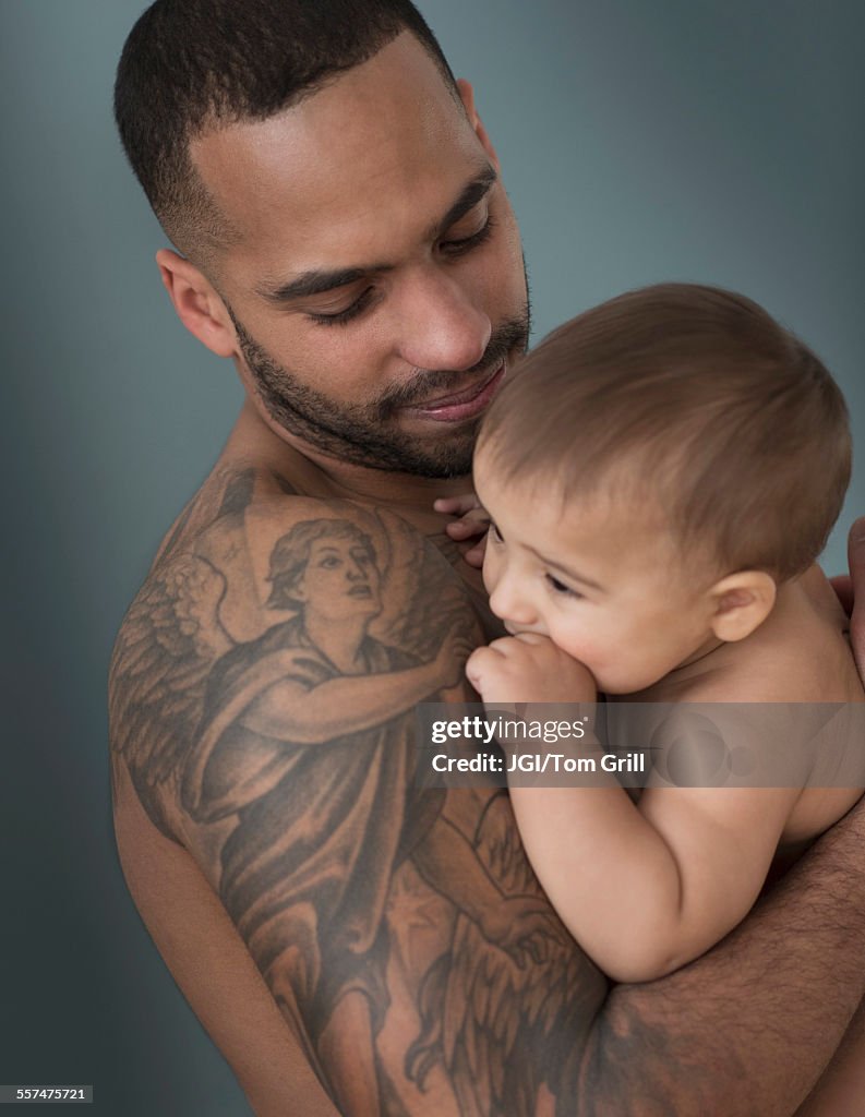 Father with tattoos holding baby son