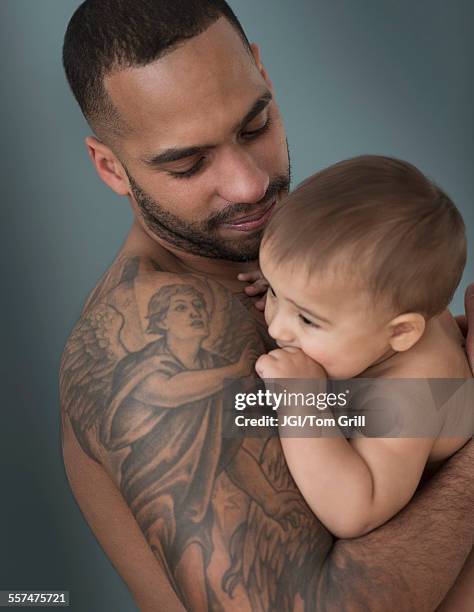 father with tattoos holding baby son - angel tattoos stock pictures, royalty-free photos & images