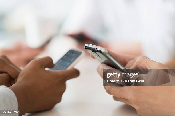 close up of friends texting with cell phones at table - social media fotografías e imágenes de stock