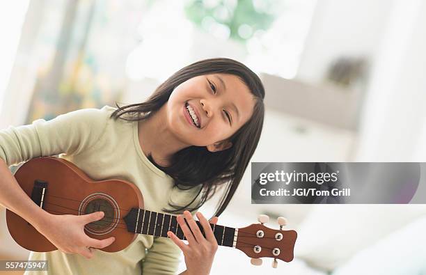 chinese girl practicing ukulele in bedroom - ukulele stock-fotos und bilder