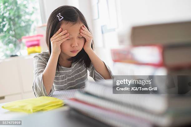 anxious chinese student rubbing forehead doing homework - headache child fotografías e imágenes de stock