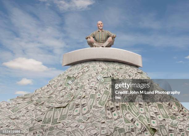 caucasian businessman sitting on mattress on mountain of money - hidden object stock pictures, royalty-free photos & images