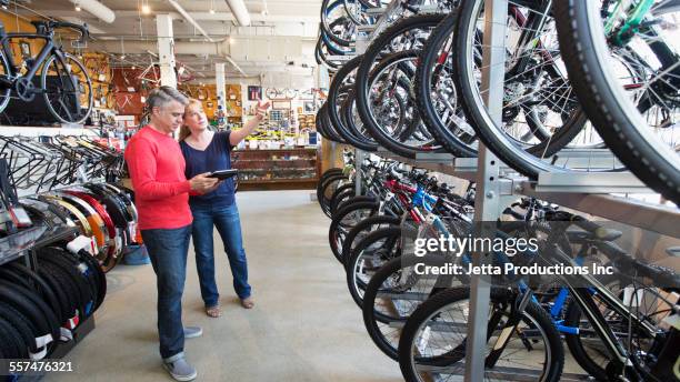 salesman showing bicycles to customer in bicycle shop - shopping with bike stock-fotos und bilder