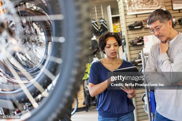 sales team using digital tablet in bicycle shop - sport shop stock-fotos und bilder