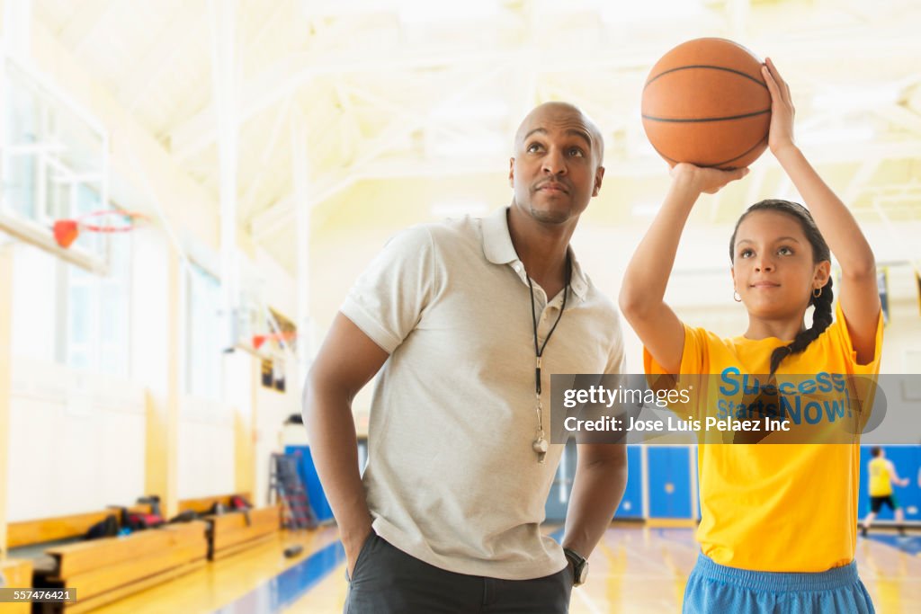 Coach teaching basketball player in gym