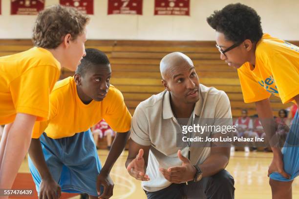 coach talking to basketball team during game in gym - talent team coaching stock-fotos und bilder