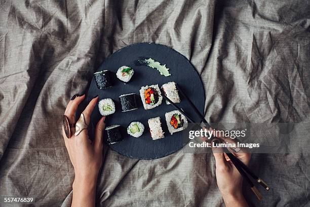 hands of woman reaching for platter of sushi on bed - nori photos et images de collection