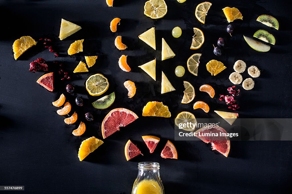 Sliced fruit arranged above juice bottle