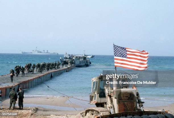 American Marines and a photographer disembark from a landing craft onto a floating pier as another such boat awaits its turn, Beirut, 1982. A...