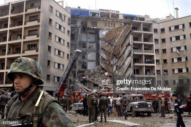 An American Marine Second Lieutenant stands with his back to rescue workers swarming the ruins of the American embassy after a suicide bomber...