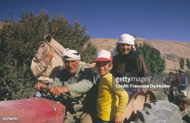 An old man and a group of workers who may be his family ride on a tractor during the hemp harvest in the Bekaa Valley, Lebanon, 1985. FDM-1516-20.