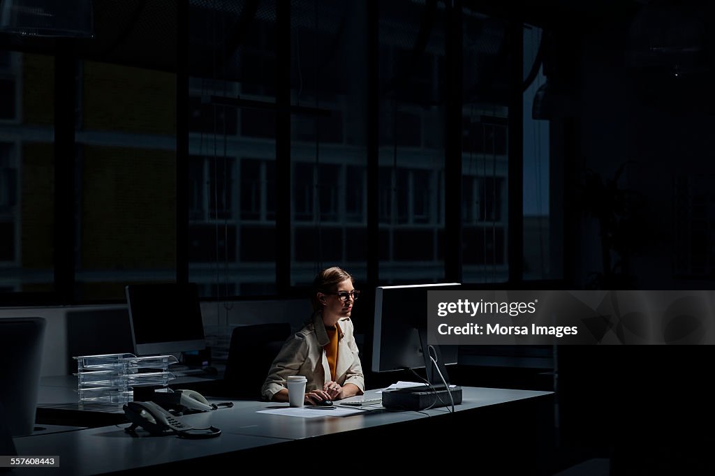 Businesswoman using computer in dark office