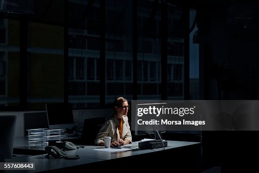 Businesswoman using computer in dark office Businesswoman using computer in dark office