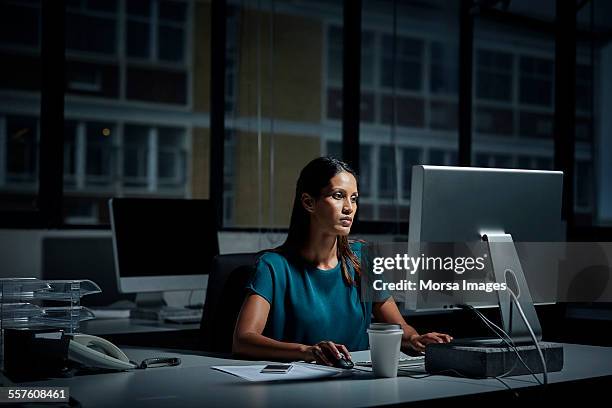 businesswoman using computer in dark office - working overtime stock pictures, royalty-free photos & images