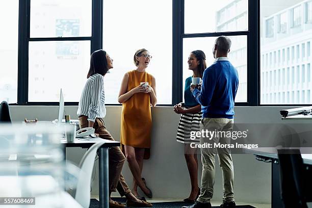 cheerful business people standing by office window - coffee break office stock-fotos und bilder