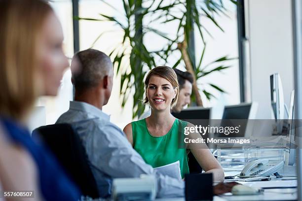 businesswoman discussing with colleague in office - green shirt stock pictures, royalty-free photos & images