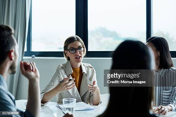 businesswoman discussing plan with colleagues - four people business talking stock pictures, royalty-free photos & images