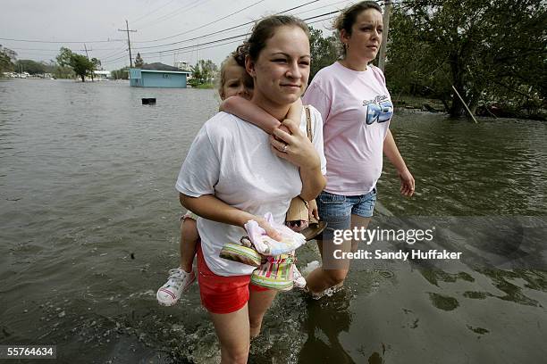 Chloe Rice , with her daughter Erica Scott, walks to higher ground, with friend Nicole Lapeyrouse as flood waters rise, due to a levy break September...