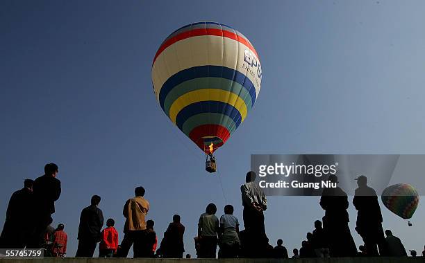 Residents look at a hot air balloon taking off September 25, 2005 on the outskirt of Beijing, China. Some 11 domestic teams with 20 hot air balloons...