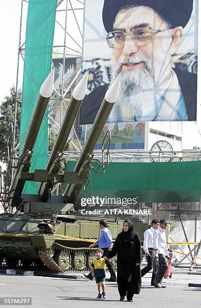 An Iranian woman walks past Russian-made Sam-6 surface-to-air missiles are seen in front of a portrait of Iran's Supreme Leader Ayatollah Ali...