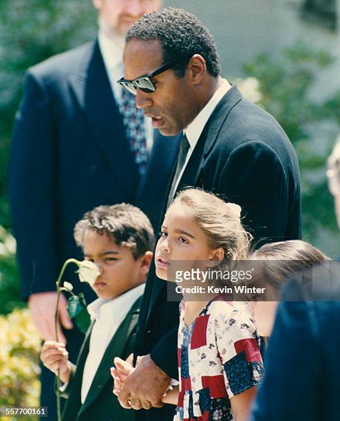 American football player and actor O J Simpson holding hands with his children Justin and Sydney at the funeral of their mother, and his ex-wife,...