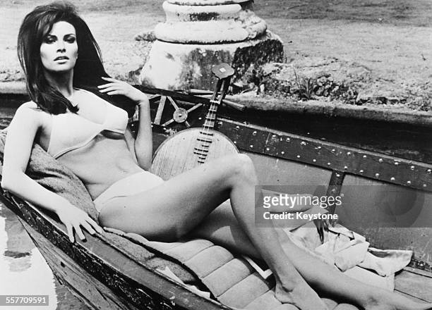 Portrait of actress Raquel Welch lying in a boat wearing a bathing suit, as she appears in the film 'The Biggest Bundle of Them All', 1966.