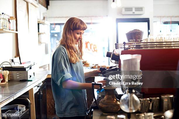 small business owner works behind cafe counter - cafeterias stock pictures, royalty-free photos & images