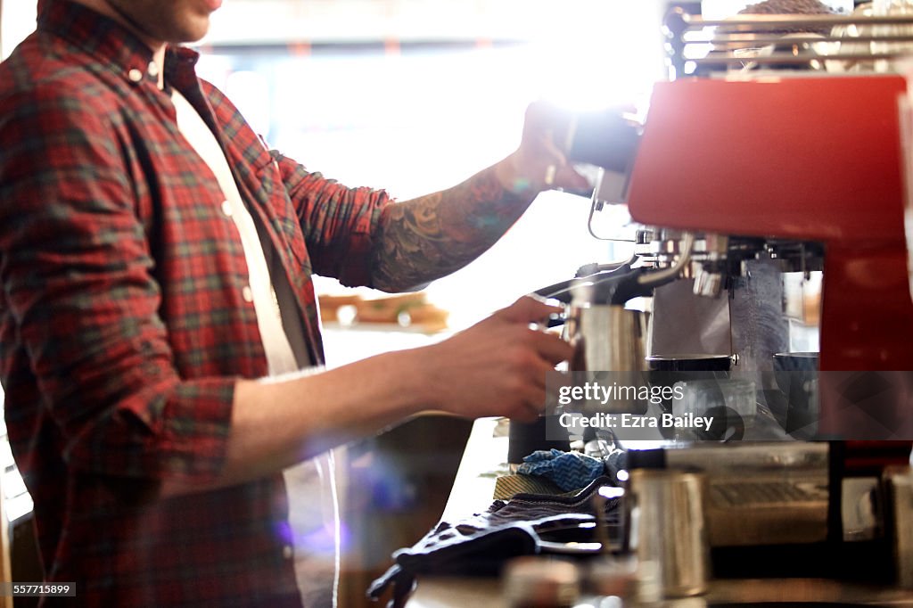 Small business owner heats milk in his coffee shop