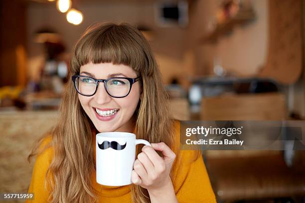 girl smiles drinking out of moustache mug - mok stockfoto's en -beelden