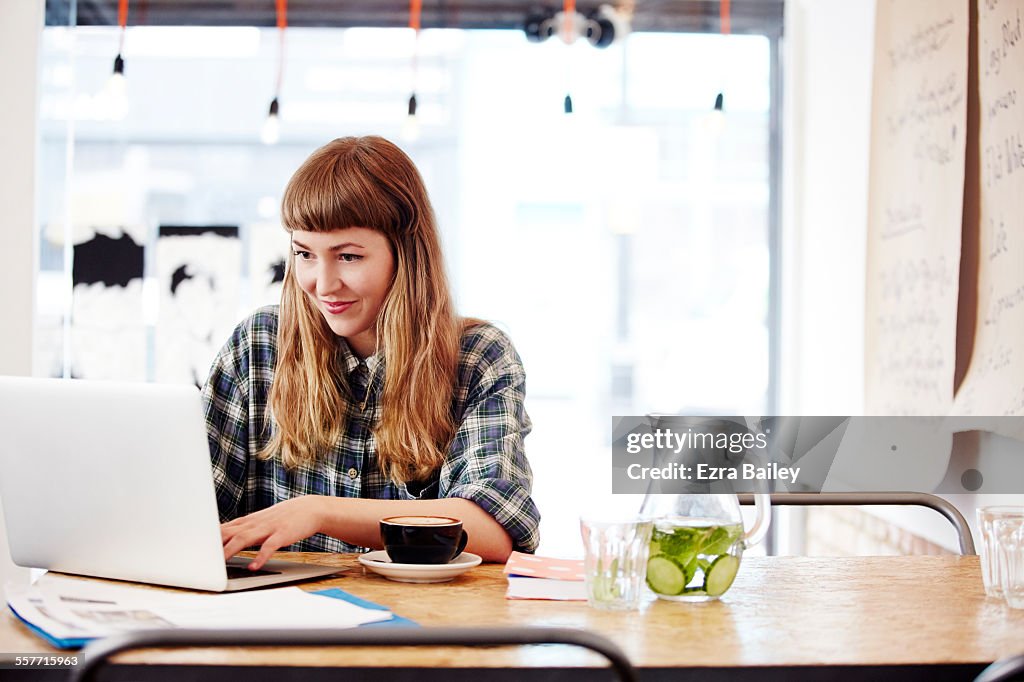 Girl working on laptop in trendy coffee shop