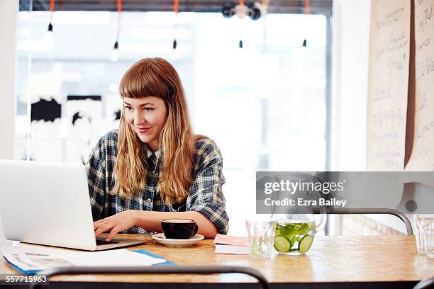 girl working on laptop in trendy coffee shop - pleased laptop fotografías e imágenes de stock
