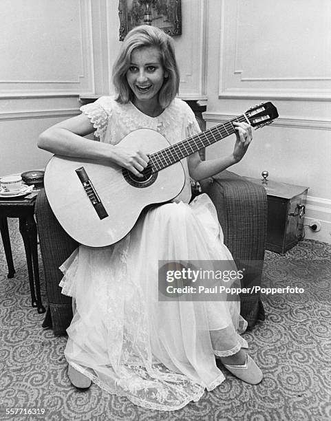 Actress Jill Ireland smiling as she practices a guitar lesson in her hotel room, London, January 10th 1969.