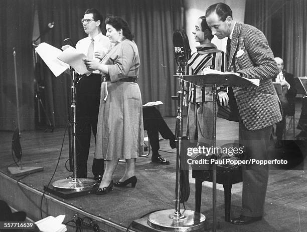 Actors Max Bygraves and Hattie Jacques, with ventriloquist Peter Brough and his puppet Archie , speaking in to radio microphones as they record the...