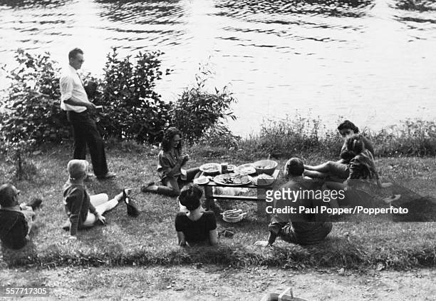 Soviet spy Eugene Ivanov gets his camera ready to take a picture, during a picnic with a group of friends, including model Catherine Keeler, next to...