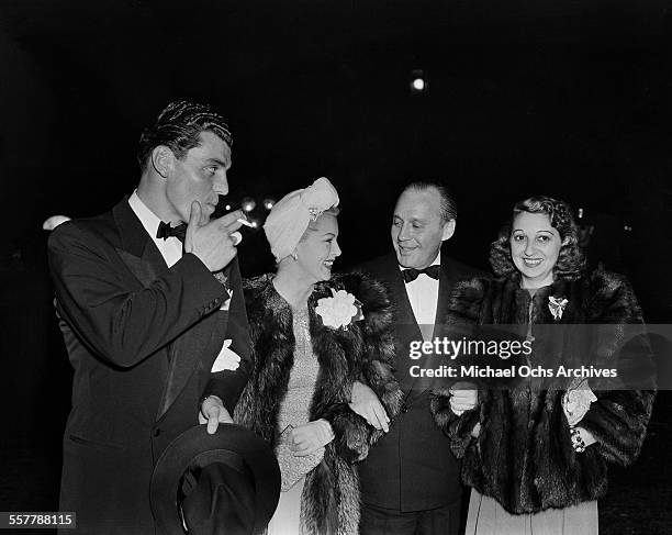 Actor Greg Bautzer and actress Lana Turner walk with Jack Benny and his wife Mary Livingston too an event in Los Angeles, California.
