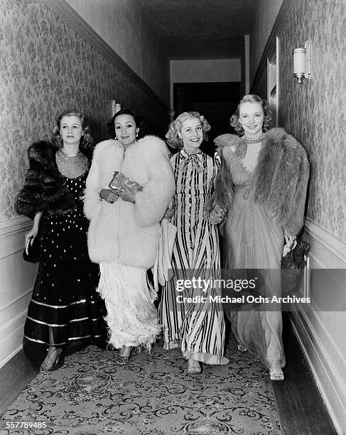 Actresses Virginia Bruce, Dolores del Rio, Anita Louise, Virginia Bruce walk down a hallway to a party in Los Angeles, California.