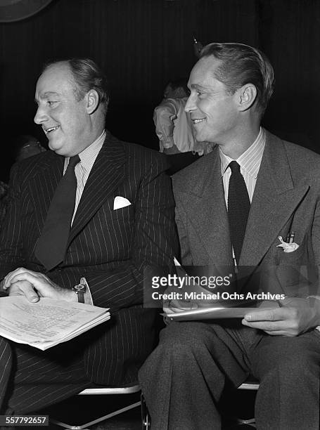 Actor Franchot Tone sits with actor Alan Mowbray during an event in Los Angeles, California.