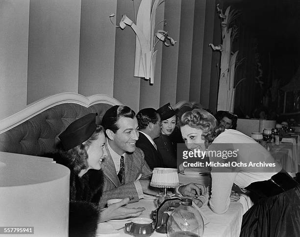 Actress Barbara Stanwyck and her husband actor Robert Taylor talk with actress Mary Livingston in Los Angeles, California.