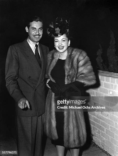 Actress Anne Baxter with husband actor John Hodiak pose on a street in Los Angeles, California.